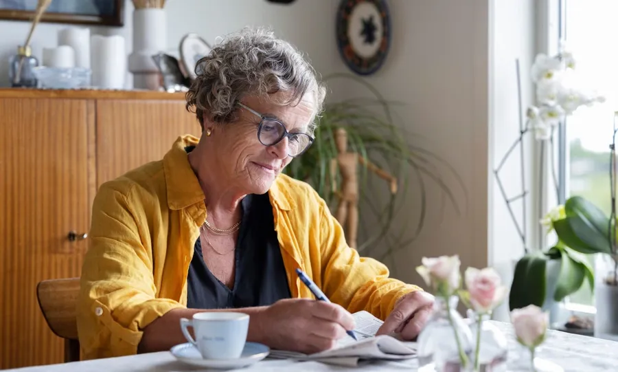 Image de Gullborg assise à sa table avec un café et un journal. Les problèmes de vessie ne sont pas rares chez les personnes atteintes de sclérose en plaques. En fait, plus de 4 personnes sur 5 atteintes de sclérose en plaques sont touchées par des problèmes de continence à un moment ou à un autre de leur vie. 