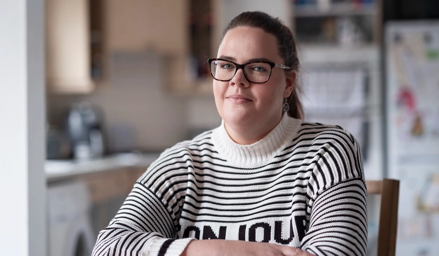 Sarah, une utilisatrice de sondes intermittentes, atteinte de sclérose en plaques, est assise à une table. 