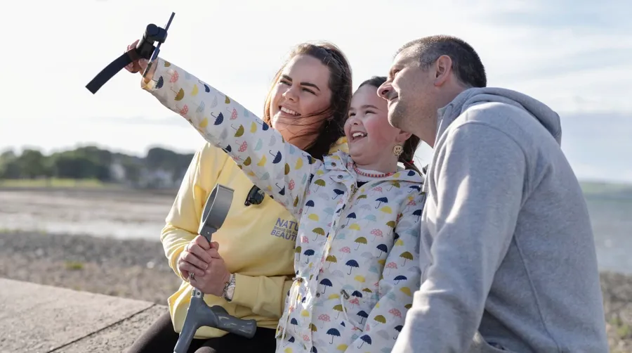 Photo de Sarah et de sa famille prenant un selfie ensemble à la plage. Il a fallu beaucoup de temps à Sarah pour faire le lien entre ses problèmes de vessie et son diagnostic de SEP.  