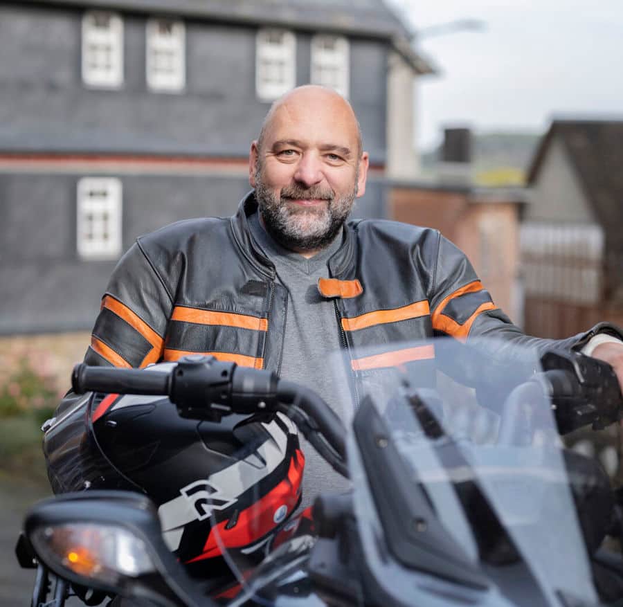 Photo portrait de Michael assis sur sa moto. Michael est atteint de sclérose en plaques et souffre de troubles vésicaux. Il a découvert que sa vessie était hyperactive et qu'il devait uriner plus souvent que les autres.