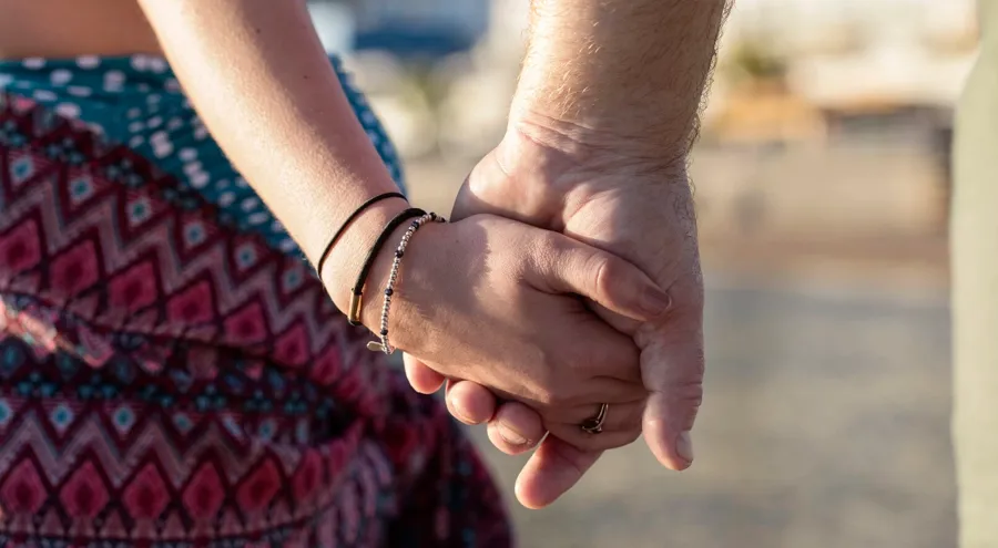 Gros plan sur un couple se tenant la main. D'autres symptômes de la SEP, tels que la fatigue, les tremblements ou les troubles vésicaux et intestinaux, peuvent perturber la vie sexuelle d'une personne. 